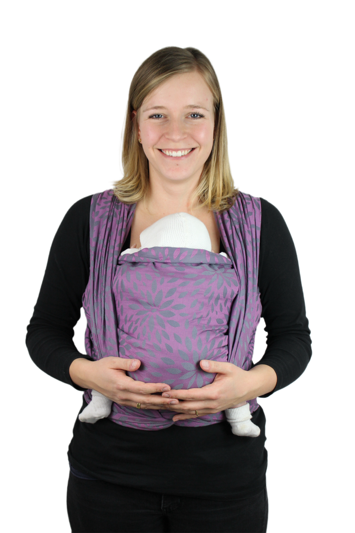 Eine Frau trägt ihr Baby vor dem Bauch im Tragetuch KAAMI Sling Flora Purple Grape, lila mit Blütenmuster.