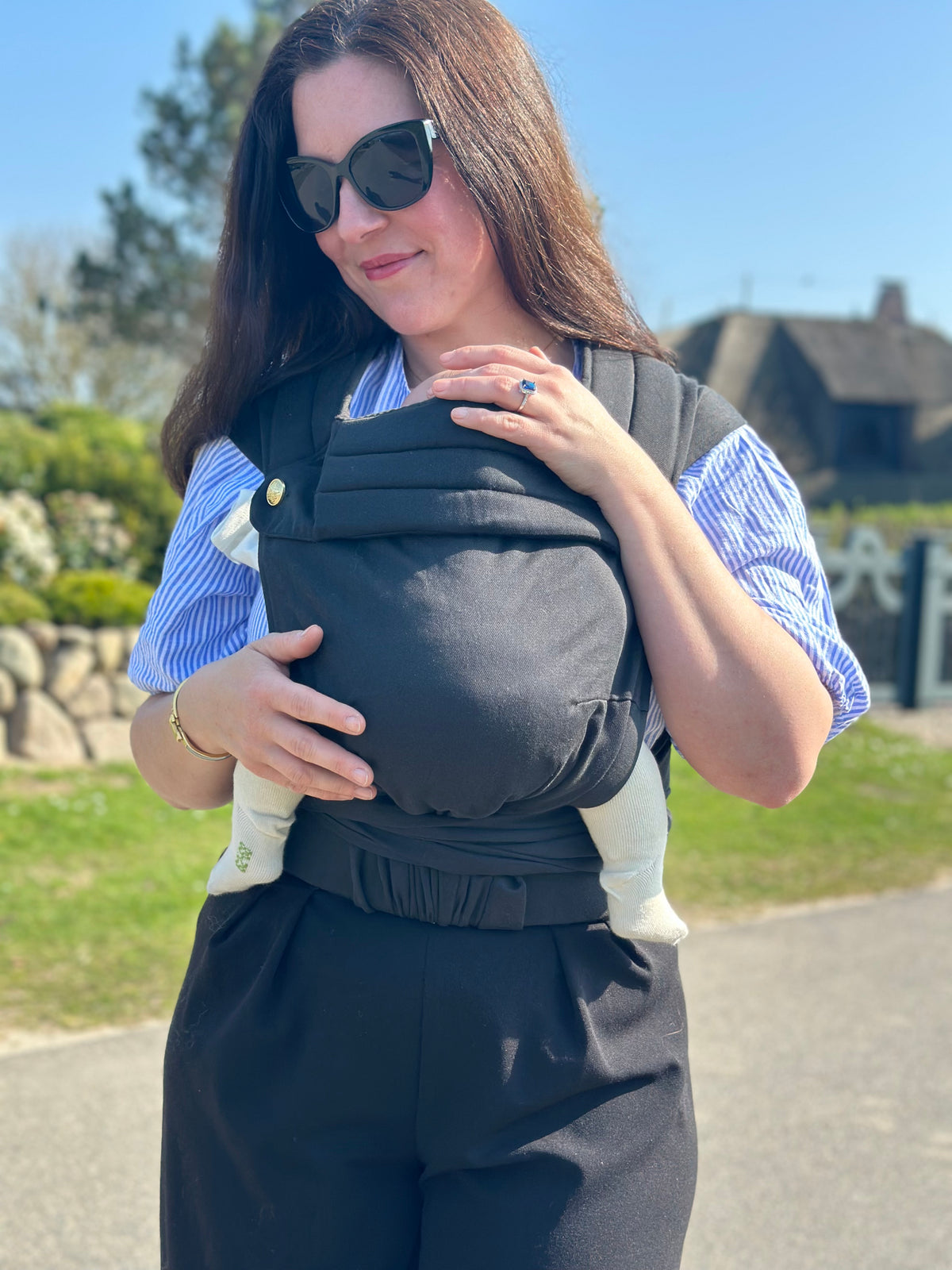 Die Frau legt die Hand an ihr Kind in der MonDoudou Noir und blickt zu ihm hinunter.